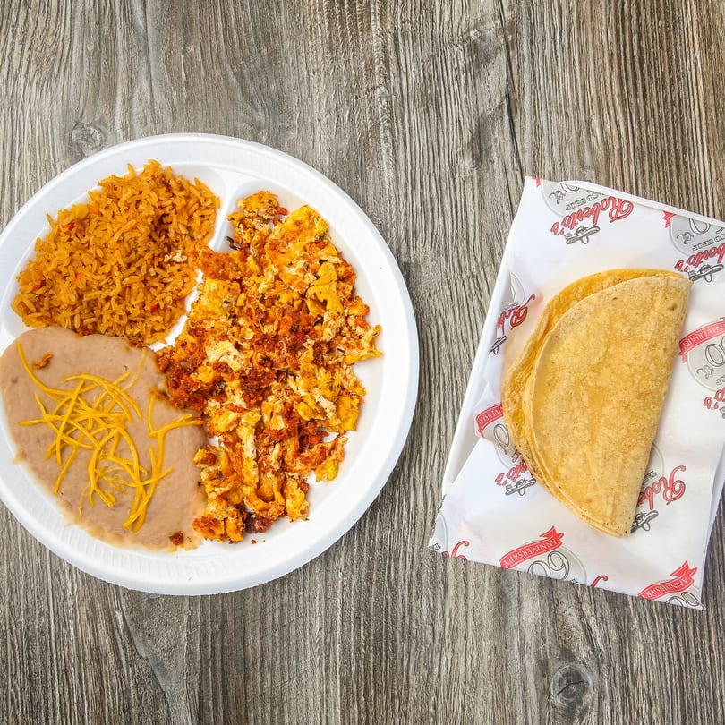 A plate of Mexican food with rice, refried beans, scrambled eggs with chorizo, and two tacos.